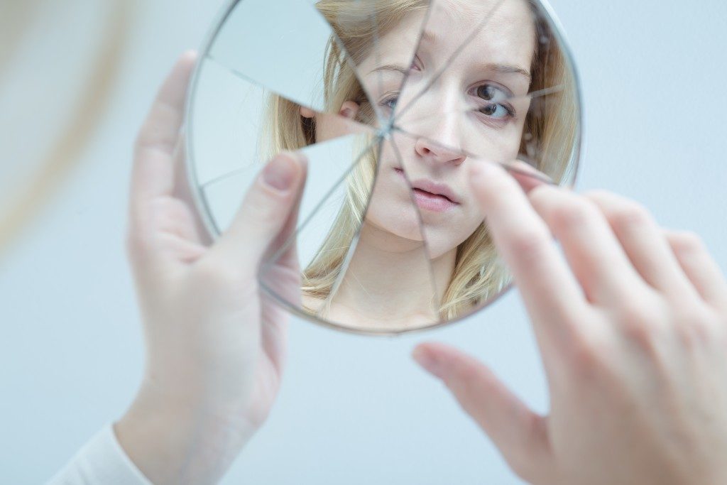 a teen looking at a broken mirror